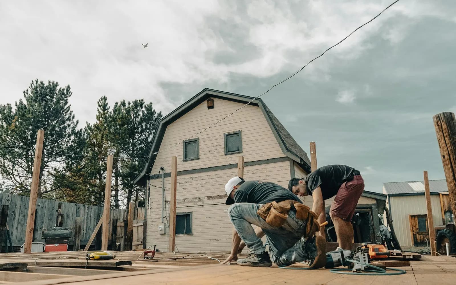 Workers building a wood deck frame beside a house.