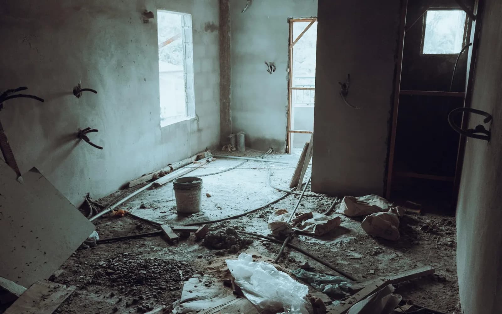 Unfinished room with bare walls and construction debris before drywall finishing.